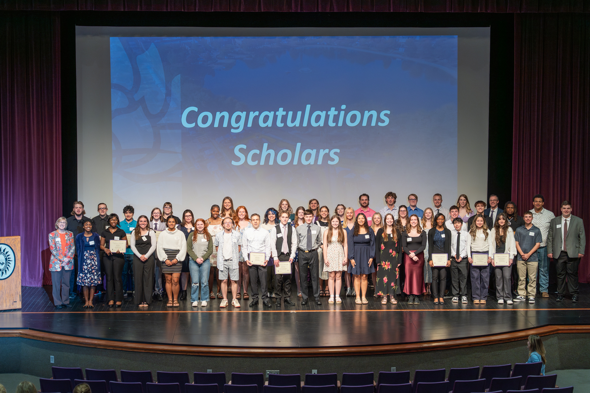 Photo of scholarship recipients standing in front of a screen that reads "Congratulations Scholars" 