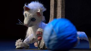 A white mouse puppet on stage