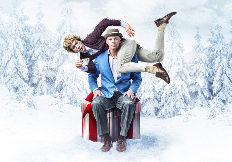 Two men sitting on a red present. One holding a teacup.