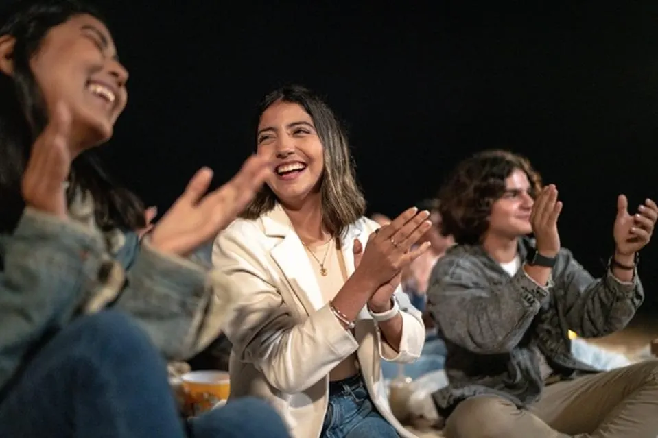 Photo of smiling students clapping and laughing together