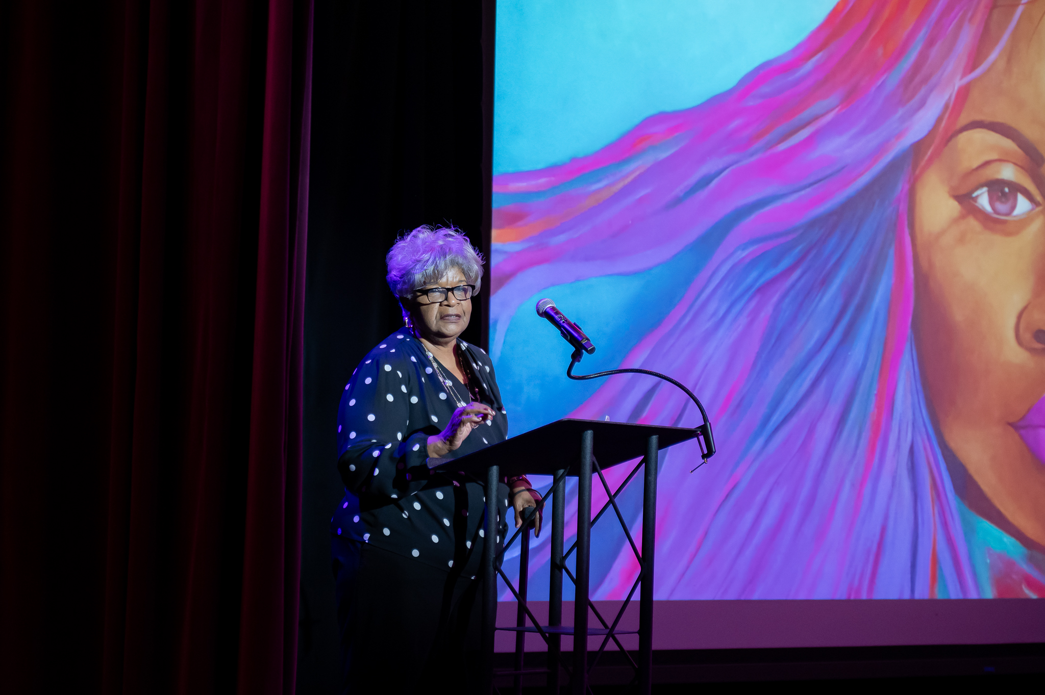 Photo of a woman speaking on stage at a conference 
