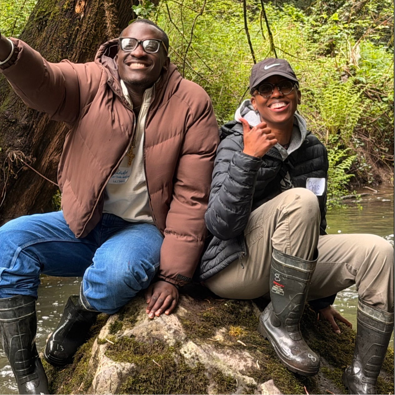 Two Blueprint mentors sitting on a rock with big smiles.