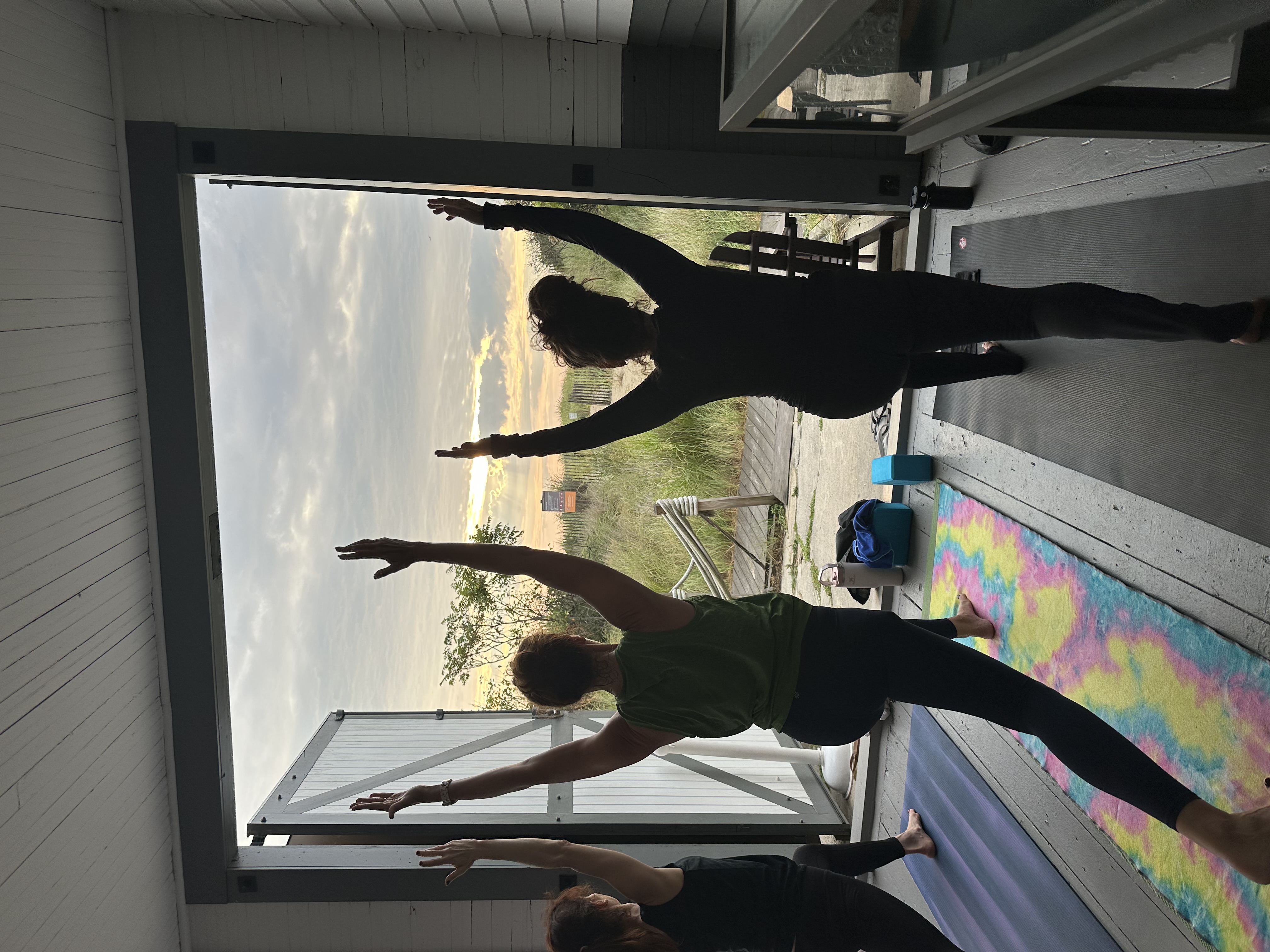sunrise yoga participants in a lunge looking out over the dunes from the lifesaving station boat room