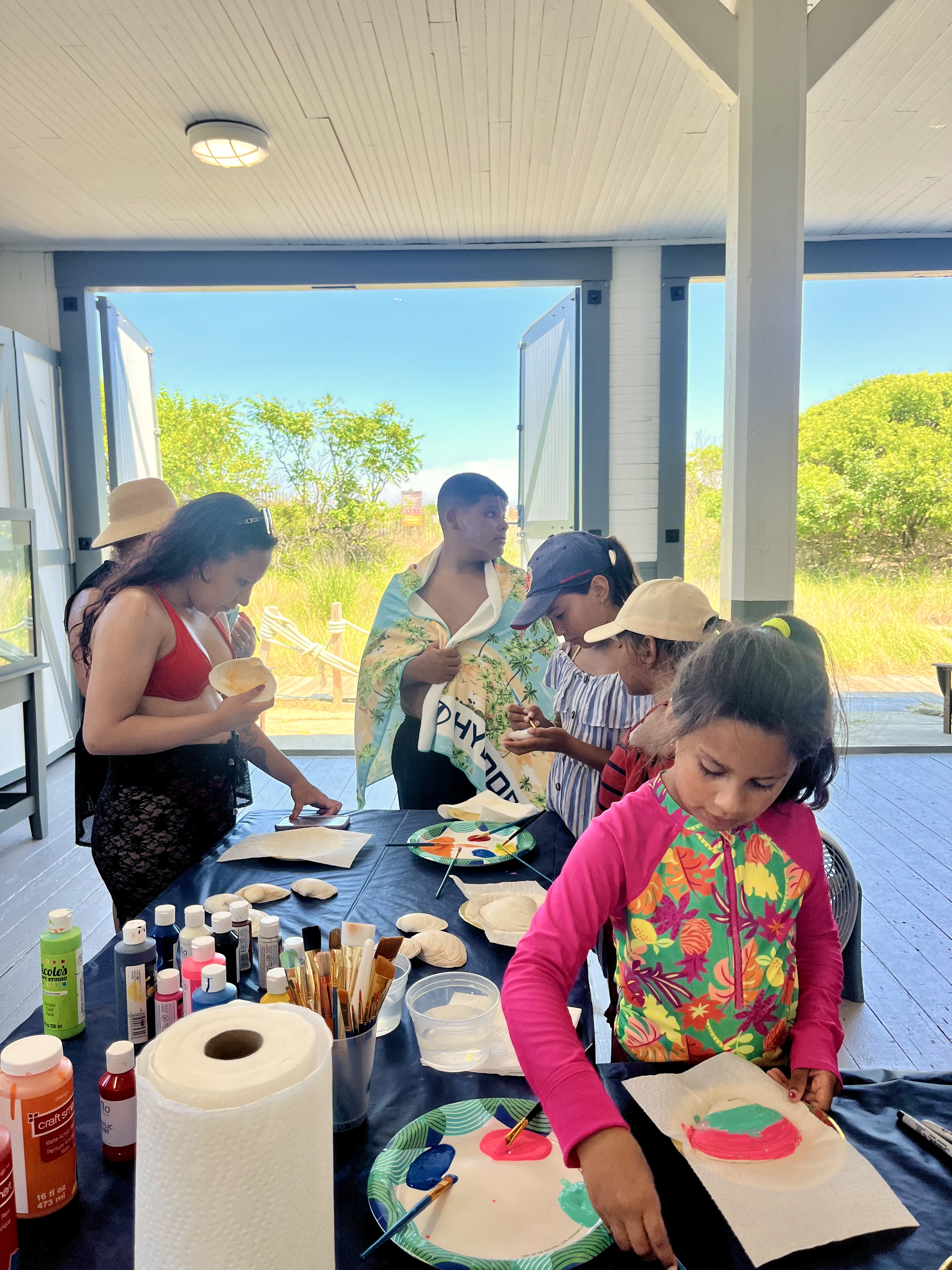 kids and teens participating in shell painting program at lifesaving station.